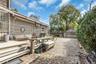 Outdoor deck with stairs, gravel driveway, detached garage, and mature perimeter landscaping