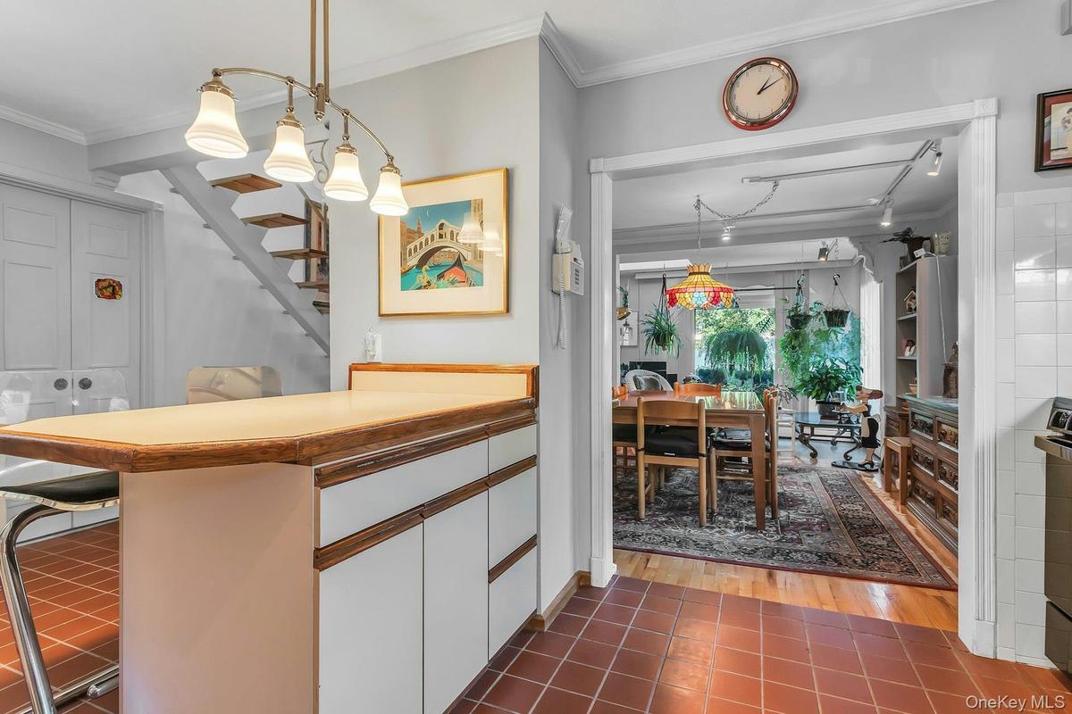 Room featuring terra cotta tile flooring, a multi-light fixture, and a built-in counter with storage