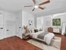 VIRTUAL STAGING. Rear private bedroom featuring walk-in closet, en-suite bath, siting area and wood-finish flooring, white doors with matte black hard