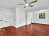 Primary bedroom featuring wood-finish flooring, two ceiling fans with integrated lighting, and doors accented with matte black hardware. House for ren