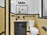 Black vanity cabinet with brass-tone hardware, rectangular wall-mounted mirror, three-light fixture, and ceramic tile wall accents featuring contrasti