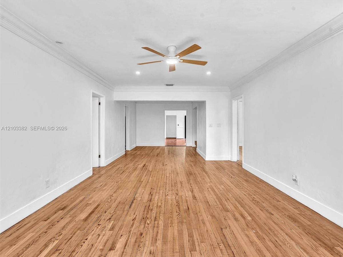 Sunny living room and dining room featuring wood-finish flooring, crown molding, recessed lighting, and ceiling fans. Home has a split design, separat