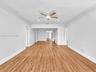 Sunny living room and dining room featuring wood-finish flooring, crown molding, recessed lighting, and ceiling fans. Home has a split design, separat