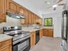 Spaceous kitchen featuring tile countertops, stainless steel appliances, a ceiling fan with integrated lighting, and tile flooring. House for rent in 