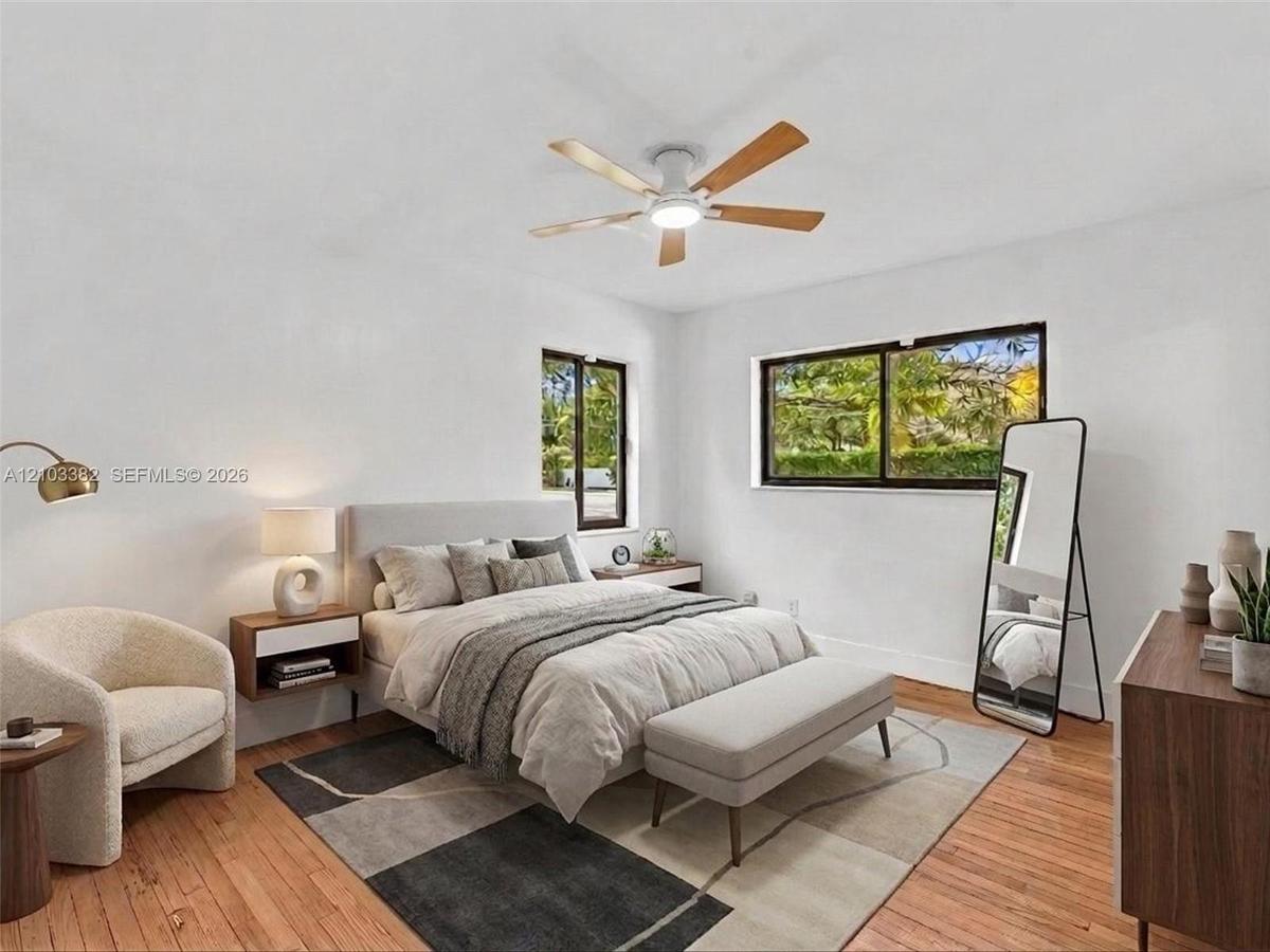 VIRTUAL STAGING. Front west bedroom with en-suite bath and closet. Featuring wood-finish flooring, two sliding windows with dark frames, and a ceiling