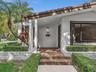 Exterior featuring a covered entryway with ceramic tile steps, white stucco siding, stacked stone landscaping walls, and a large picture window. House