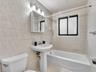 Full bathroom featuring a pedestal sink, a bathtub with a tiled surround, a mirrored medicine cabinet with integrated lighting, and a window