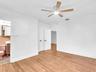 West front bedroom with en-suite bath and closet. Wood-finish flooring throughout, ceiling fan with integrated lighting, and white interior doors with