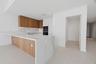 Kitchen featuring wood-finish cabinetry, waterfall-edge stone island, integrated wall oven, neutral-tone large-format floor tile, and under-cabinet li