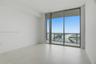 Floor-to-ceiling glass windows, large format tile flooring, and a private balcony featuring a metal railing