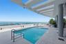 Rooftop swimming pool featuring wood-finish decking, a glass panel railing, and an overhead architectural trellis