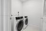 Dedicated utility area featuring white ceramic tile flooring and louvered door access