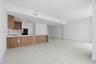 Modern kitchen featuring wood-finish cabinetry, solid-surface countertops, built-in wall oven, and large-format tile flooring