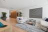 Living space featuring wood-finish flooring, recessed lighting, vertical wood wall paneling, and floor-to-ceiling glass wall partitioning