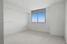 Bright room featuring large-format tile flooring, neutral white walls, and a large sliding glass window with metal framing