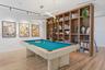 Custom floor-to-ceiling built-in wood shelving unit with integrated vertical slat detailing, linear pendant lighting, track lighting, and wood-finish 
