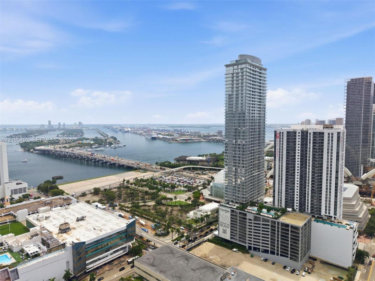 High-rise exterior featuring floor-to-ceiling glass paneling and expansive balcony structures, set against an urban waterfront landscape
