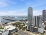 High-rise exterior featuring floor-to-ceiling glass paneling and expansive balcony structures, set against an urban waterfront landscape