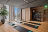 Fitness space featuring wood-finish flooring, floor-to-ceiling windows with horizontal wood louvers, flush-mount lighting, and wall-to-wall wood panel