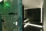 Steam room finished with large-format green stone slab wall cladding, integrated perimeter floor lighting, and built-in stone bench seating