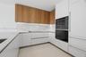 Kitchen featuring two-tone cabinetry with wood-finish upper units and white lower cabinetry, light-toned stone-finish countertops, full-height stone-f