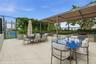 Outdoor terrace featuring a metal-framed pergola, built-in outdoor kitchen with stainless steel cabinetry, paved flooring, and a fenced recreation cou
