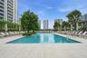 Swimming pool featuring a tiled deck, integrated metal handrails, and surrounding mature trees