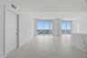 Open-concept interior featuring large-format tile flooring, floor-to-ceiling glass windows, and a built-in stone-finish counter