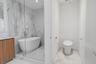 Bathroom featuring a glass-enclosed wet room with a freestanding soaking tub, wood-finish vanity cabinetry, and large-format stone-patterned tile floo