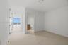 Interior space featuring neutral large-format tile flooring, recessed ceiling lighting, and a bathroom equipped with a wood-finish vanity and integrat