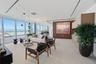 Floor-to-ceiling glass walls, light-toned wood-finish flooring, wood-paneled accent wall, recessed track lighting, and integrated ceiling-mounted ligh