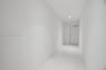 Hallway featuring neutral-toned tile flooring, recessed ceiling lighting, and a solid-core interior door with a silver-finish lever handle
