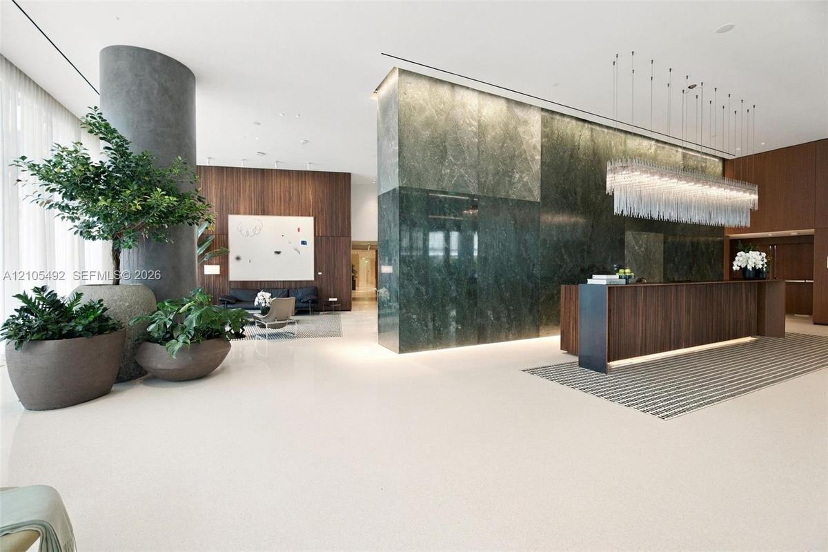 Lobby featuring stone wall cladding, wood-finish wall paneling, built-in reception desk, polished flooring, and tiered glass pendant lighting