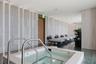 Built-in soaking tub with a tiled surround and metal grab rails, featuring floor-to-ceiling textured stone wall paneling, integrated vertical accent l
