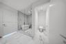 Enclosed wet room featuring a freestanding soaking tub, floor-to-ceiling glass paneling, stone-patterned tile flooring, wall-mounted shower hardware, 