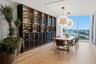 Modern dining space with wood-finish flooring, a custom black cabinetry wall featuring glass-front display cases and wine storage, pendant lighting, a