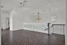 Wood-finish flooring, matte black metal railings, frosted glass safety panels, starburst-style chandelier, and recessed lighting