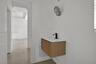 Wall-mounted floating vanity with reeded wood-finish cabinetry, white countertop, and matte black single-handle faucet