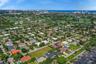 Aerial perspective of a residential neighborhood featuring expansive green space, mature landscaping, and proximity to the coastline