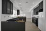 Kitchen featuring dark-toned shaker-style cabinetry, stone flooring, recessed lighting, and crown molding