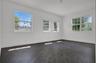 Interior space featuring dark wood-finish flooring, white walls, and multiple multi-pane windows with grid detailing