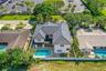 Two-story residence featuring a dark-toned tile roof, exterior stucco finish, private swimming pool, and stone-paver pool deck enclosed by white perim