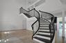Curved staircase with iron balusters, high ceilings, stone flooring, and built-in cabinetry