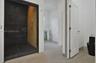 Walk-in shower with dark large-format tile surround, integrated linear drain, wall-mounted handheld shower fixture, light wood-finish flooring, and bl