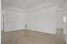 Interior space featuring a recessed tray ceiling, crown molding, and large-format neutral tile flooring
