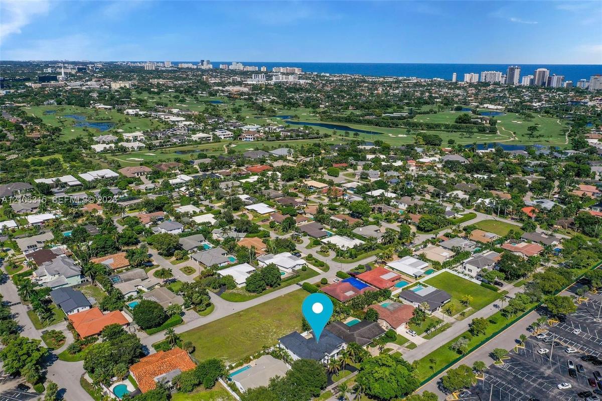 Aerial perspective showcasing a coastal suburban location with prominent proximity to golf course grounds and ocean horizon lines