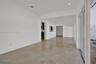 Neutral-toned large-format tile flooring, recessed ceiling lighting, and expansive multi-panel sliding glass door system