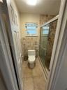 Tiled shower enclosure with a glass door, wall-mounted showerhead, and a window for natural light