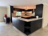 Spacious kitchen featuring a large central island, dark wood-finish cabinetry, light stone countertops, and recessed lighting