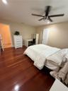 Rich wood-finish flooring with a modern ceiling fan and neutral wall tones